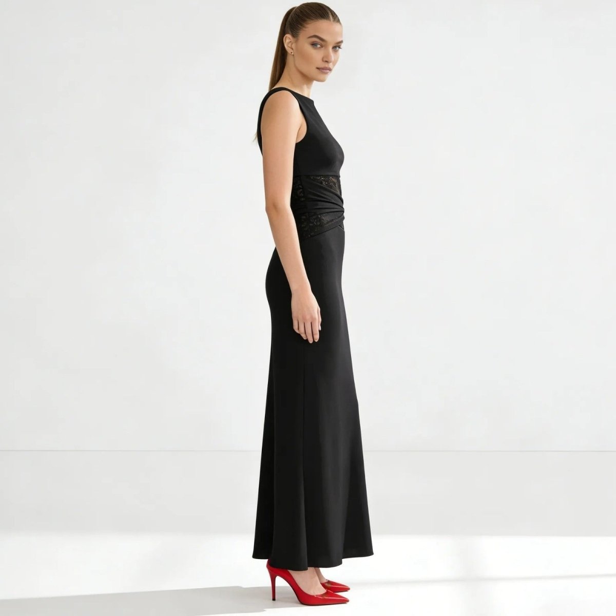 Side profile of a model in the Kouvr black bodycon midi dress, highlighting the slim fit and below-the-knee length.