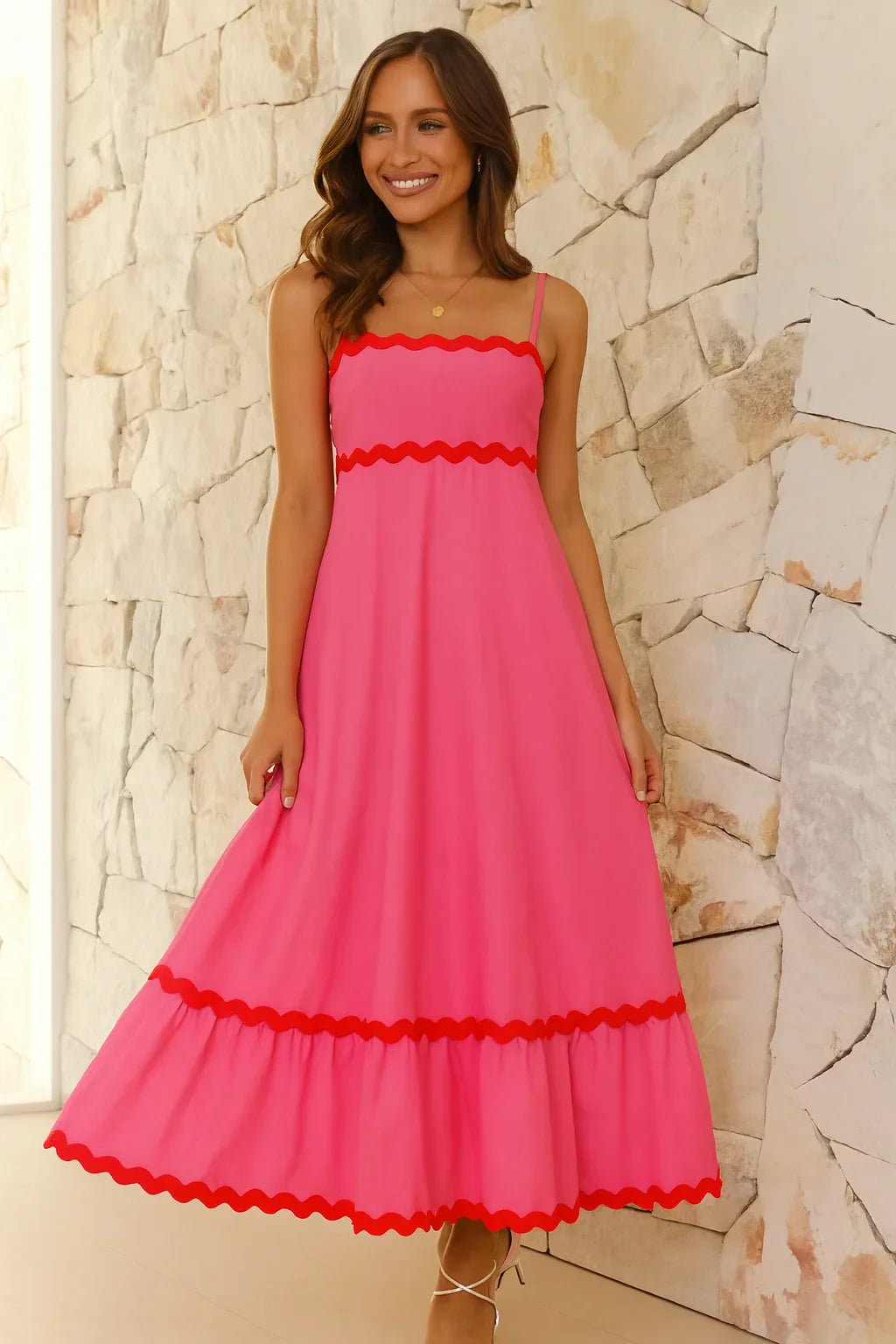 Model wearing the Kouvr Amillia pink scalloped maxi dress in front of a stone wall