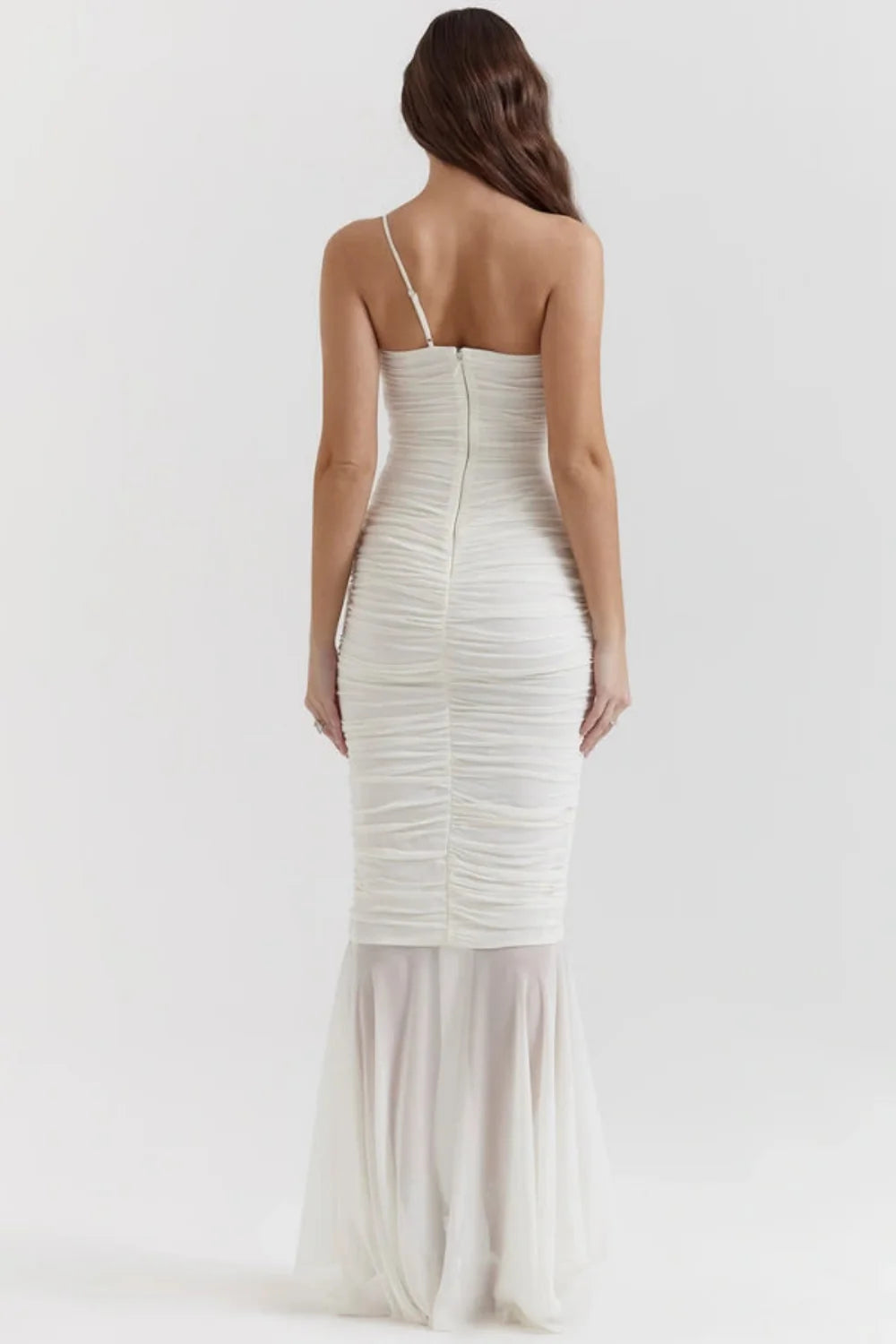 Model wearing the Kouvr Fashion Ruched white one-shoulder ruched maxi dress with a sheer mermaid hem and thigh-high slit