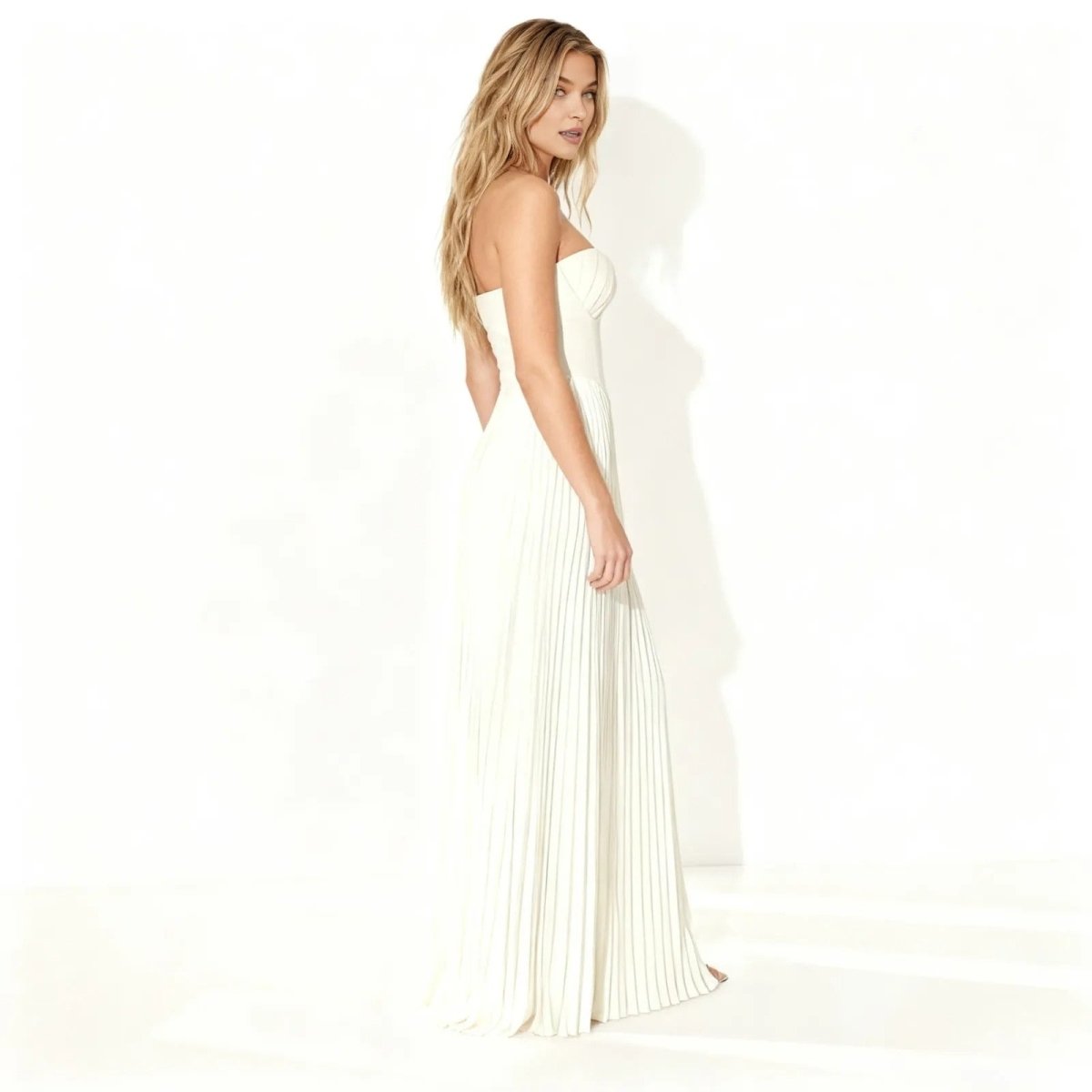 Woman wearing a ivory kouvr strapless gown on a white background