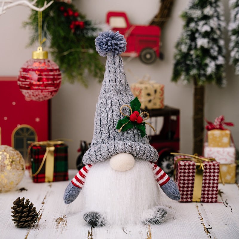 A single grey Scandinavian Christmas gnome with a long white beard and knit hat with a pompom, sitting on a white wooden table surrounded by wrapped presents.