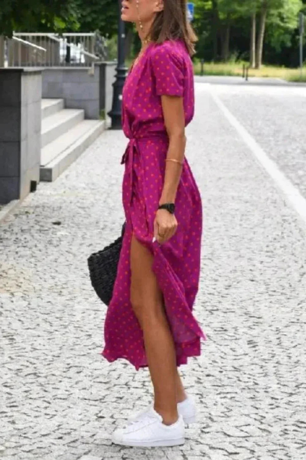 Side view of the Aleia fuchsia polka dot wrap dress, showing the high leg slit.