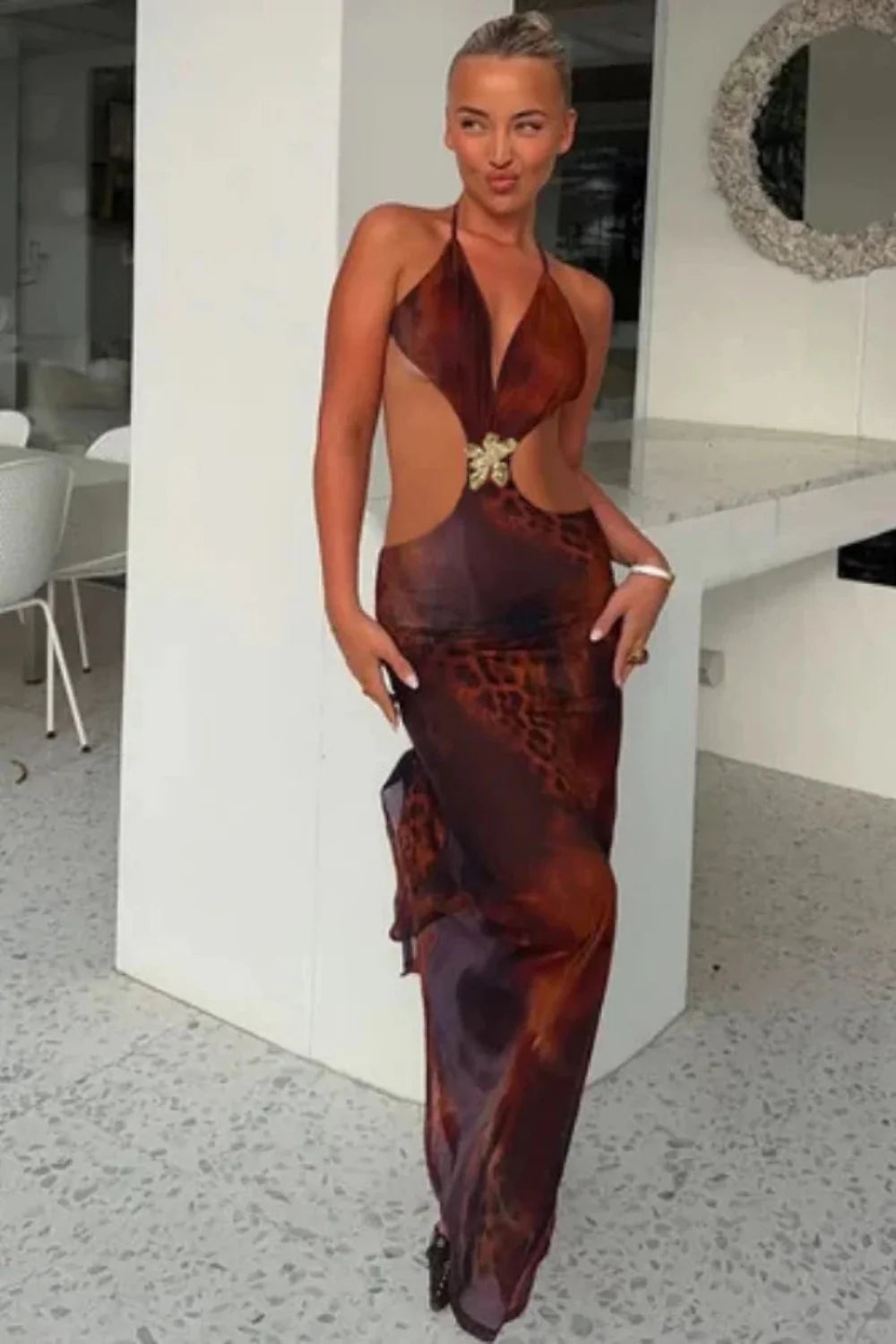 Model wearing the Kouvr Alexa brown leopard print cutout maxi dress with a halter neck and gold butterfly detail