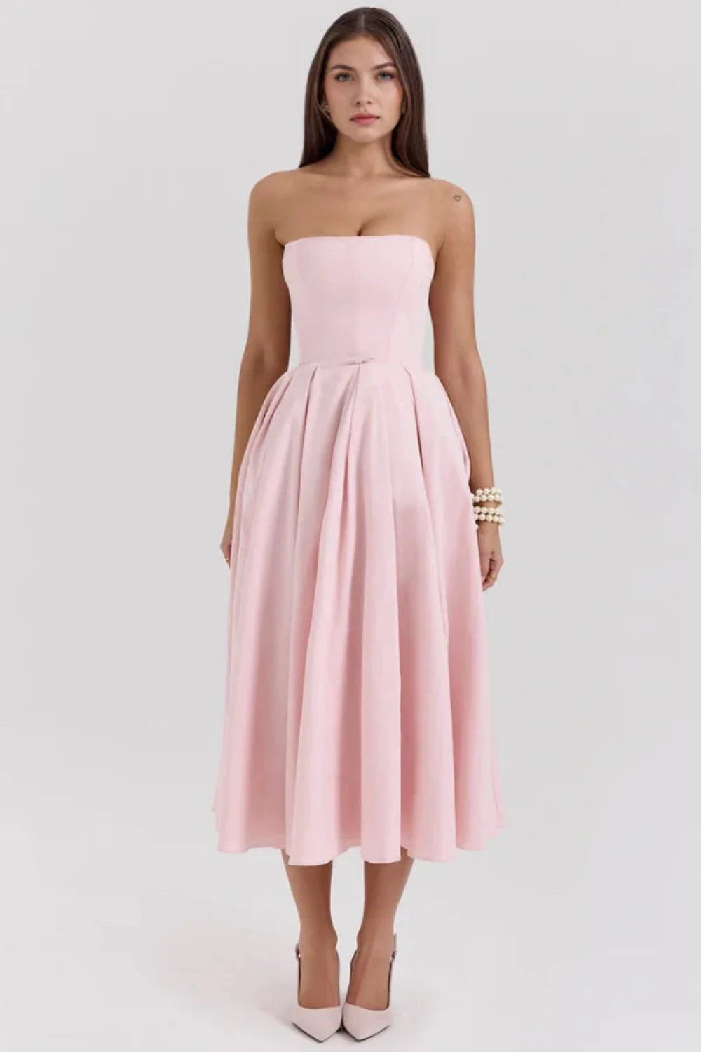 Model wearing the Kouvr Fashion blush pink strapless midi dress with a full pleated skirt