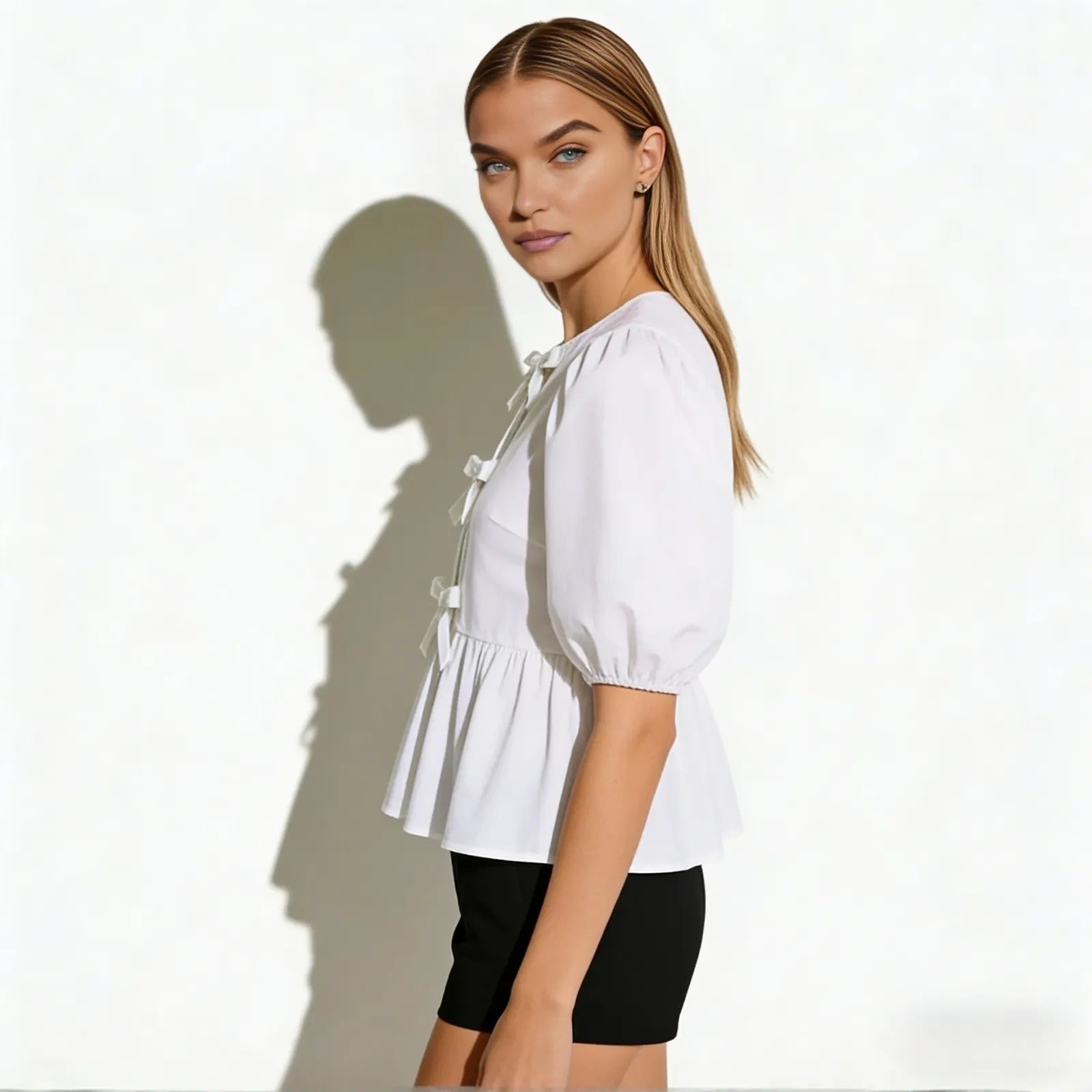 Side view of a model in the Kouvr Anne white puff sleeve blouse showing the peplum hem and sleeve volume.