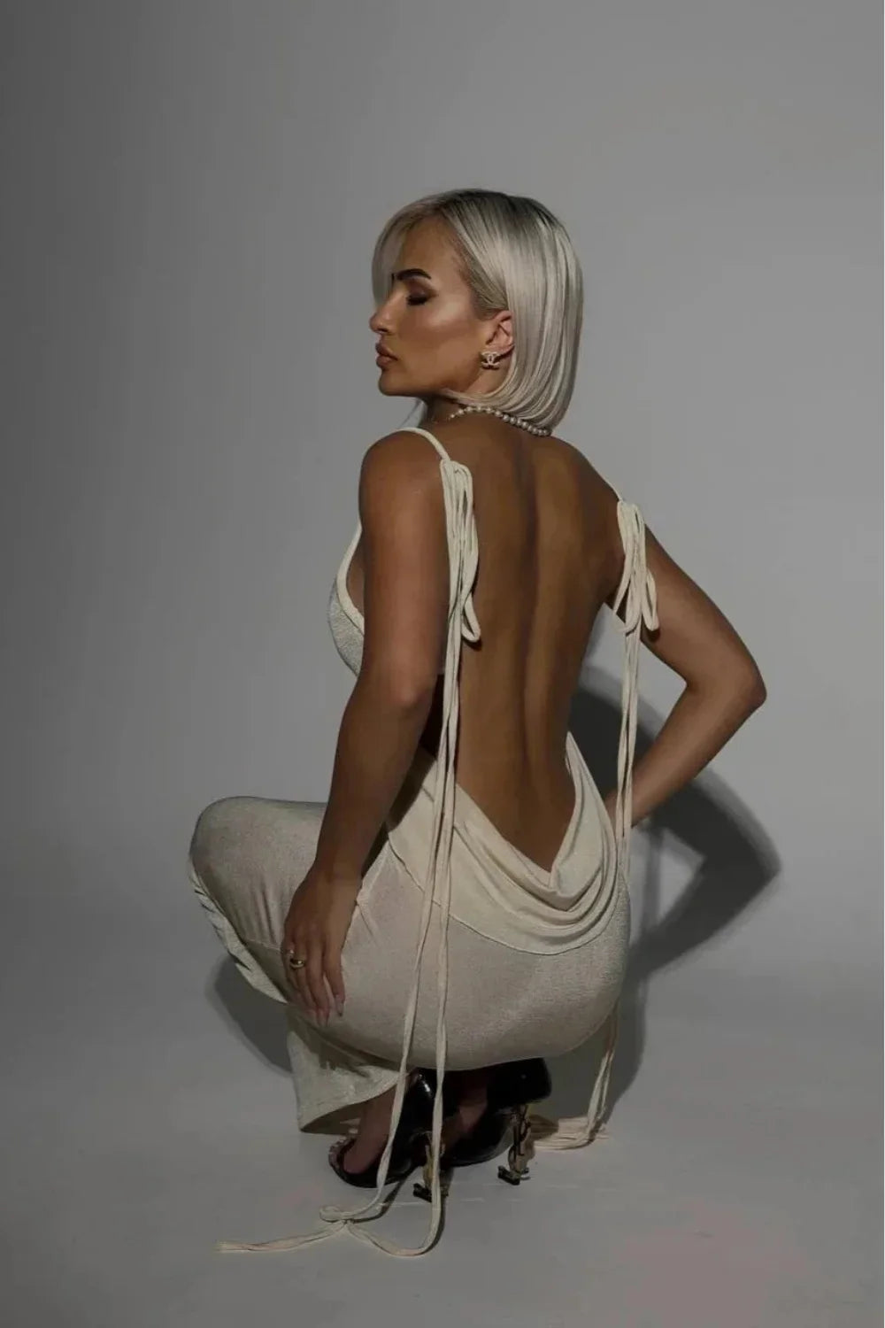 Front view of a woman wearing the Kouvr Ari white cowl neck backless maxi dress