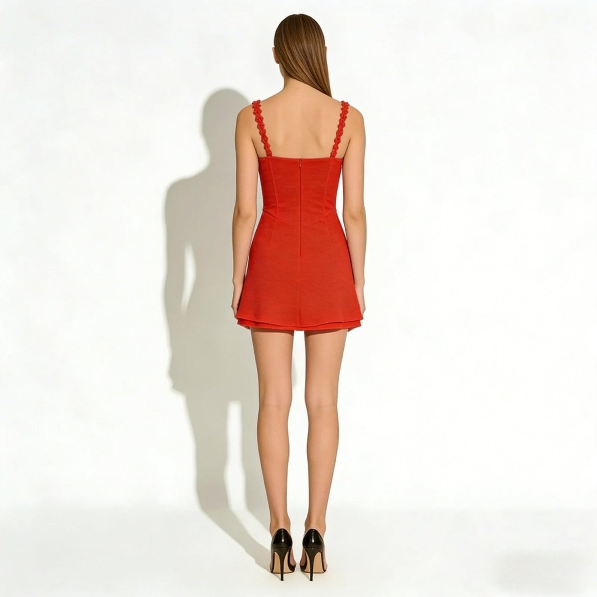Back view of a model wearing the Kouvr Ariadne red mini dress, showing the scalloped straps and concealed zipper detail.