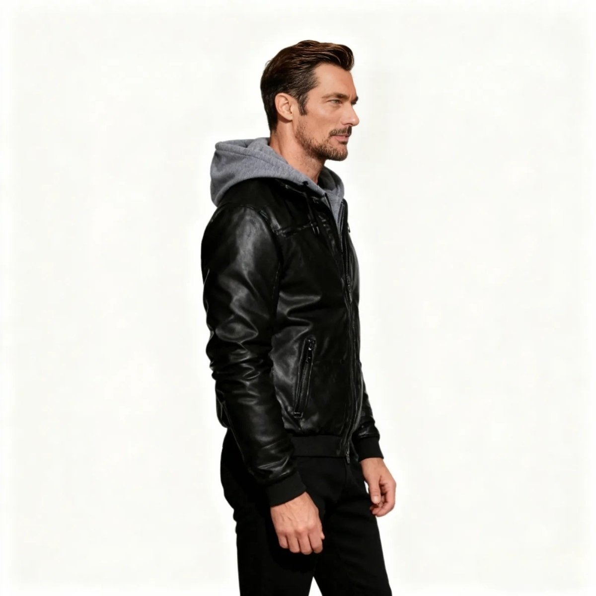 Side profile view of a man in the Kouvr Ascend black hooded leather jacket, highlighting its sleek silhouette and fit.