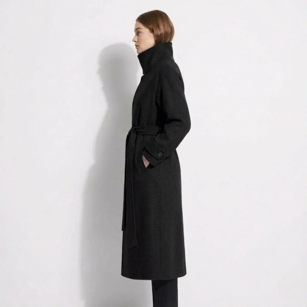 Side profile of the Kouvr Ashley long black wool wrap coat showing its length and silhouette on a model.