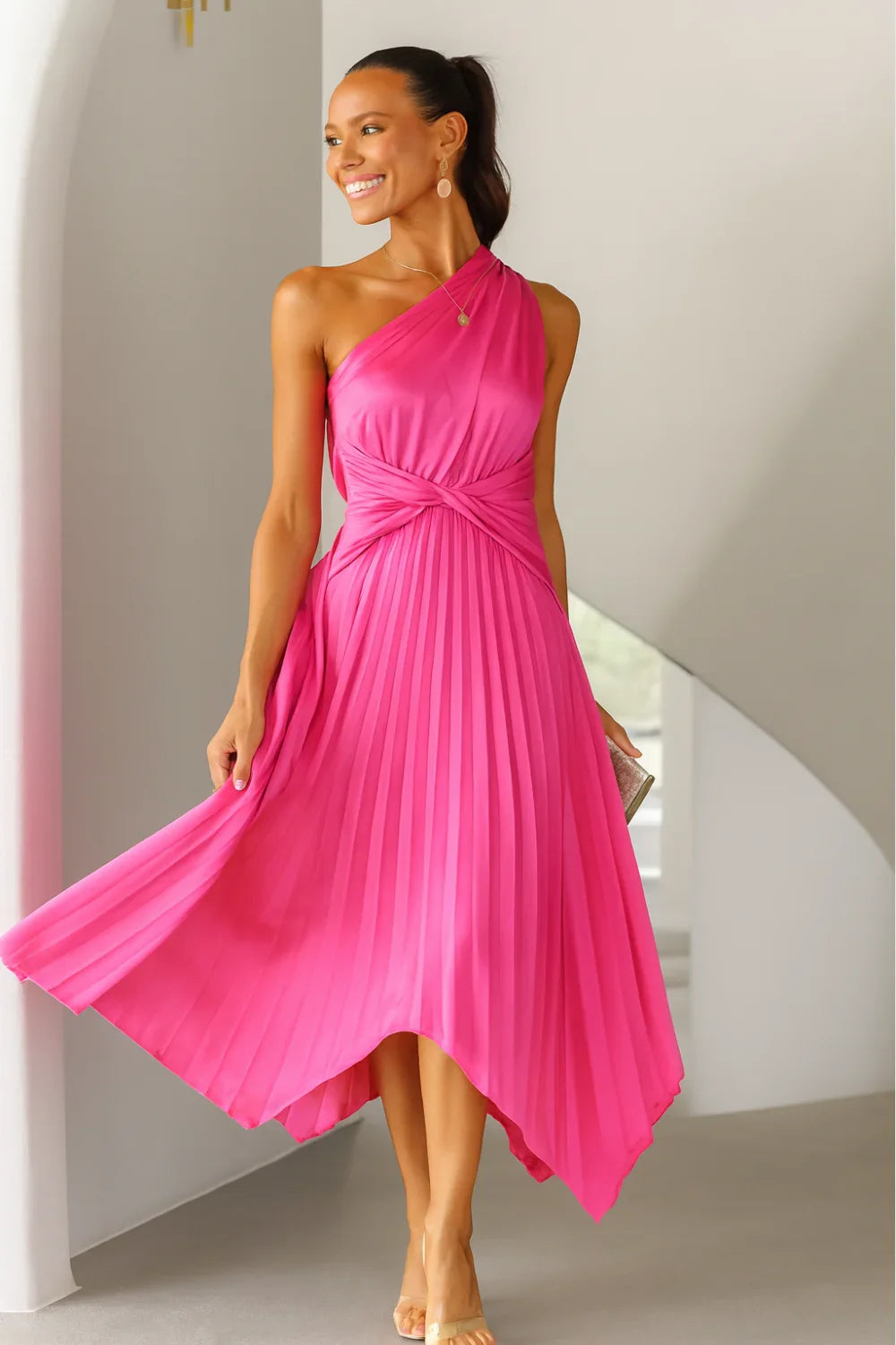 Woman wearing Kouvr Fashion hot pink one shoulder pleated dress with a white clutch' and 'Detail shot of the twist knot waist on a satin pink cocktail dress