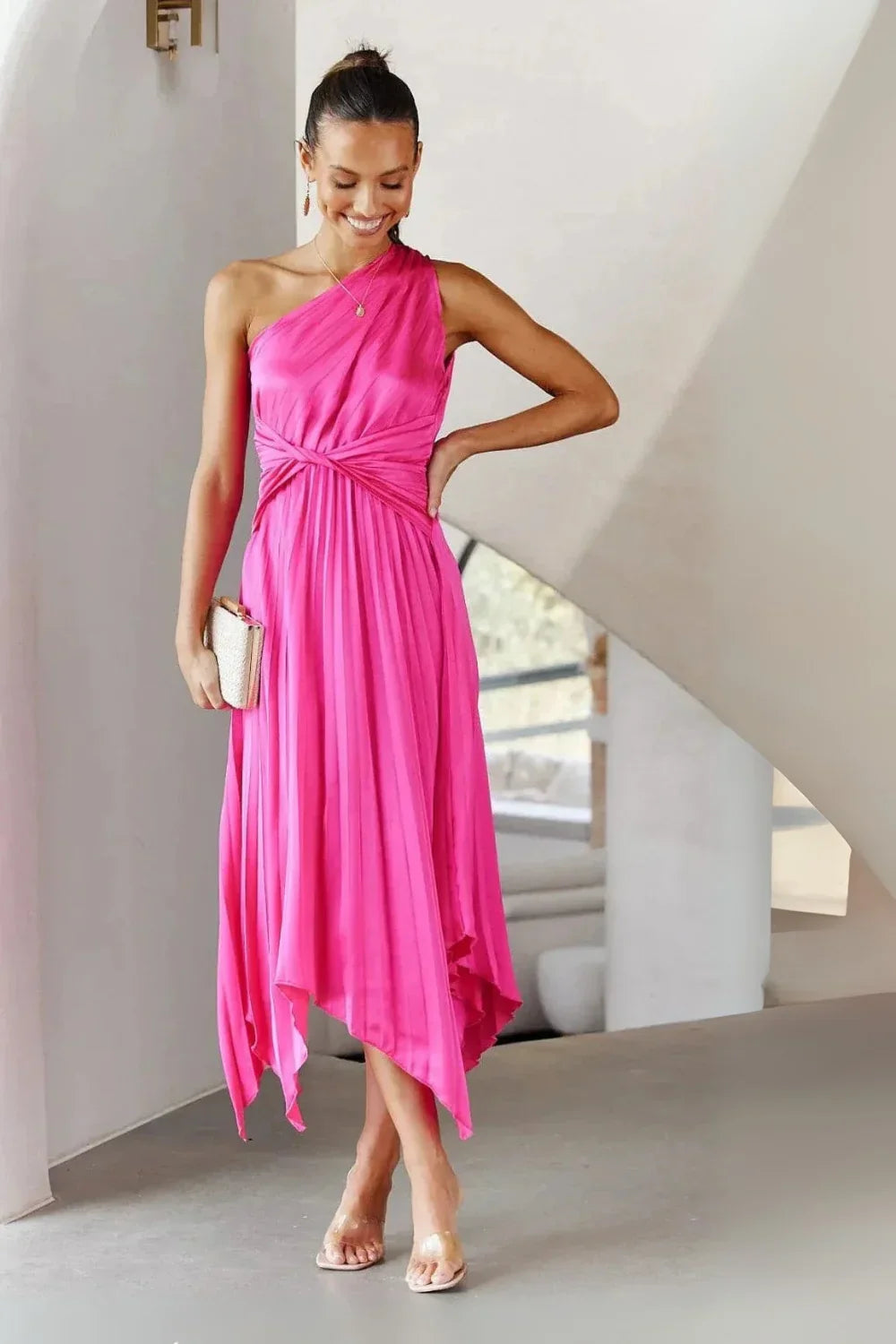 Woman wearing Kouvr Fashion hot pink one shoulder pleated dress with a white clutch' and 'Detail shot of the twist knot waist on a satin pink cocktail dress