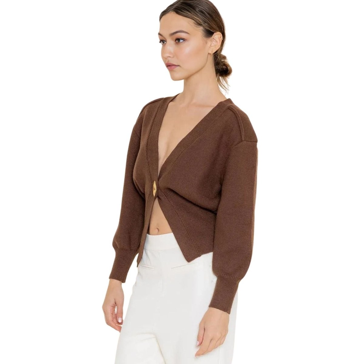 Woman wearing a brown kouvr cropped cardigan over a white top on a white background