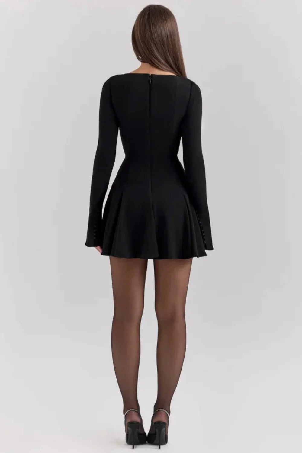 Model from behind wearing the Kouvr Fashion black long sleeve mini dress, showing the button details on the split cuffs