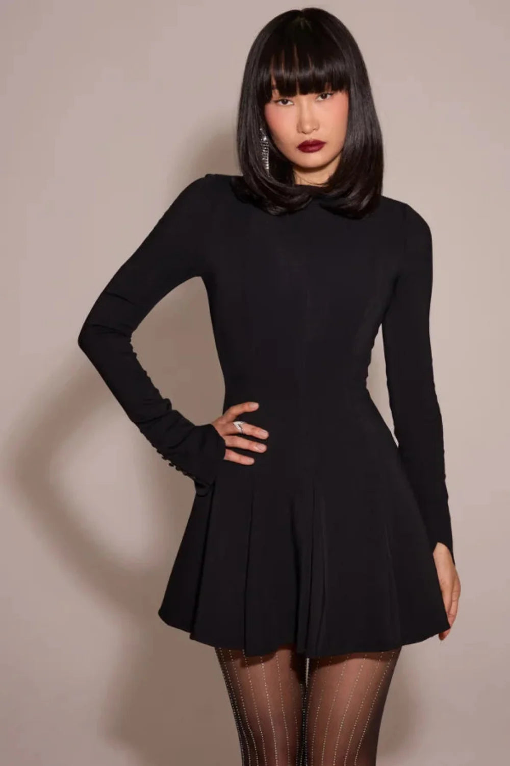 Model from behind wearing the Kouvr Fashion black long sleeve mini dress, showing the button details on the split cuffs