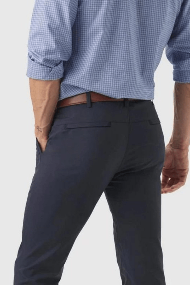 Model wearing the Kouvr Dark Blue Pant in navy with a light blue dress shirt and white leather sneakers