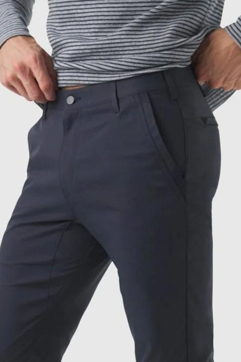 Model wearing the Kouvr Dark Blue Pant in navy with a light blue dress shirt and white leather sneakers