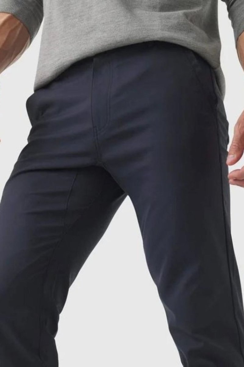 Model wearing the Kouvr Dark Blue Pant in navy with a light blue dress shirt and white leather sneakers