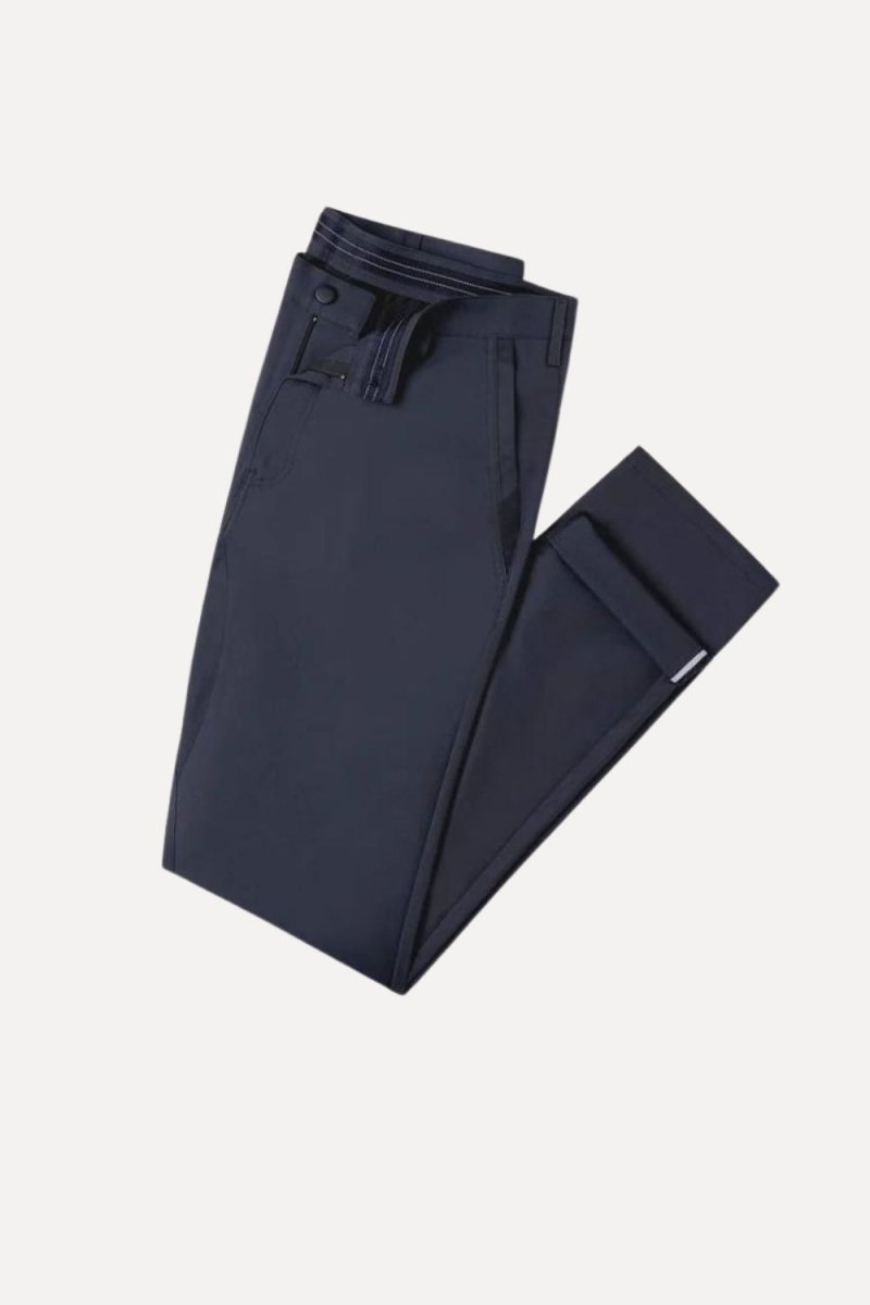 Model wearing the Kouvr Dark Blue Pant in navy with a light blue dress shirt and white leather sneakers