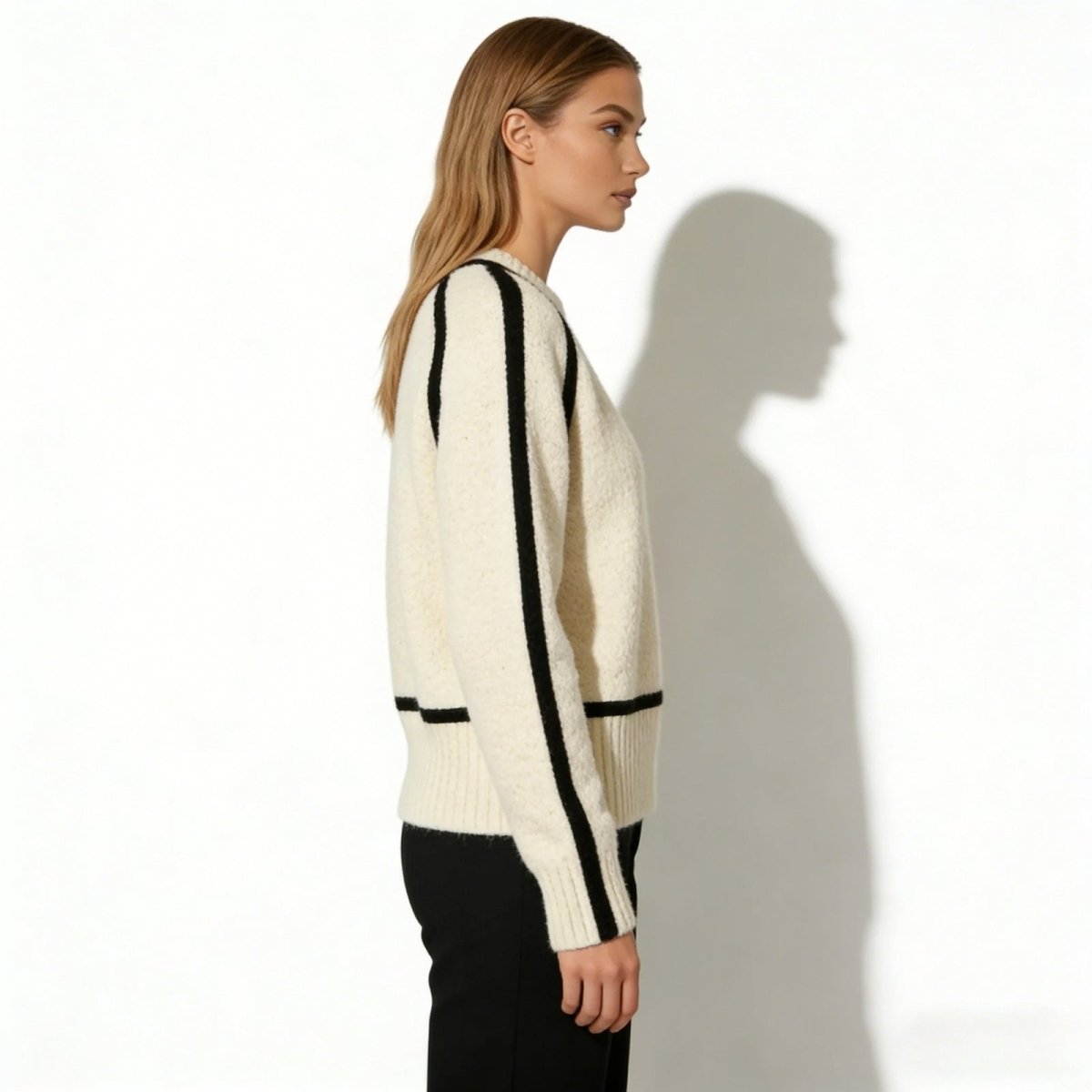 Side profile of a woman in a relaxed-fit white turtleneck showcasing the black raglan sleeve piping detail.
