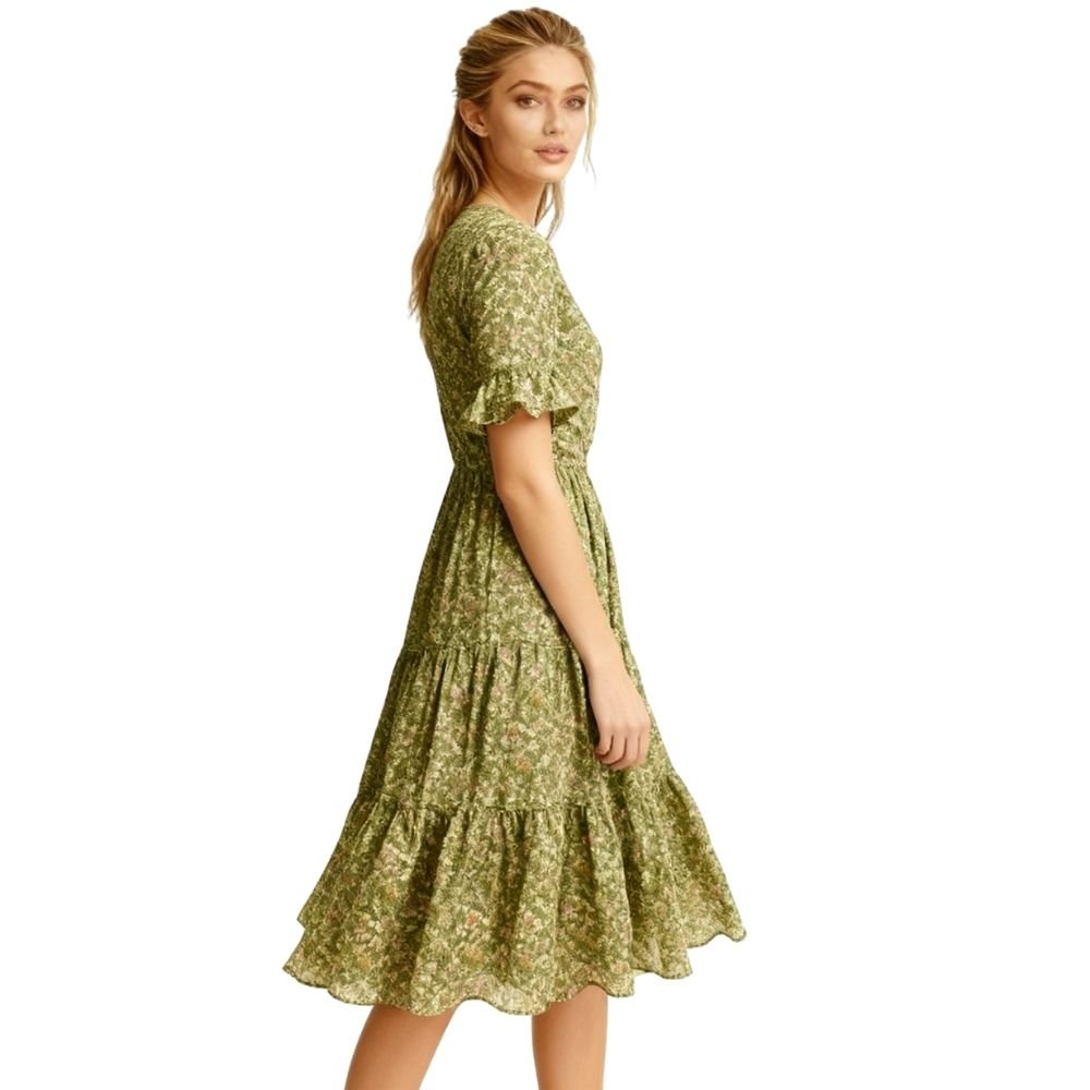 Woman wearing a green kouvr floral dress on a white background