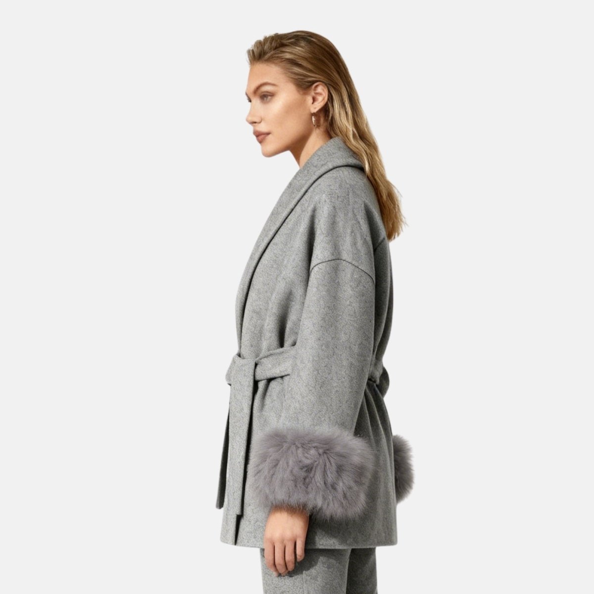 Woman wearing a gray coat with fur cuffs on a white background