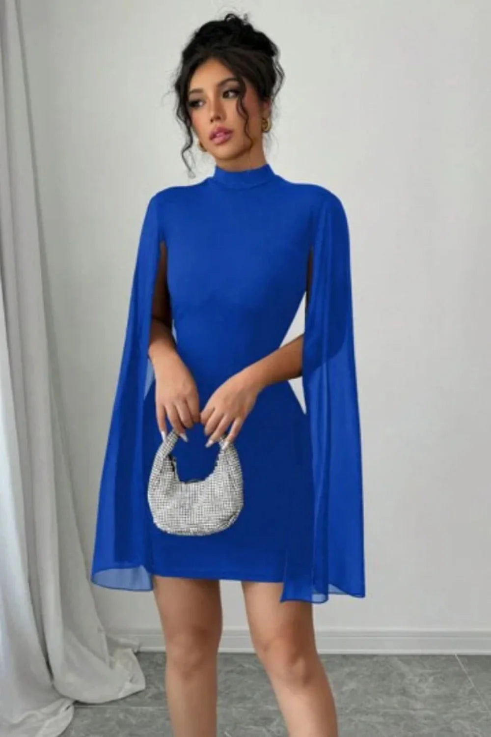 Woman wearing Kouvr Fashion's Eya blue mock neck bodycon dress with sheer cape sleeves