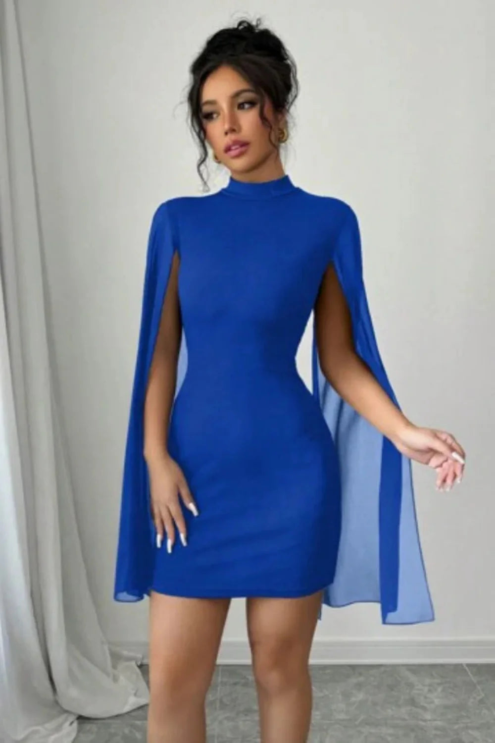 Woman wearing Kouvr Fashion's Eya blue mock neck bodycon dress with sheer cape sleeves