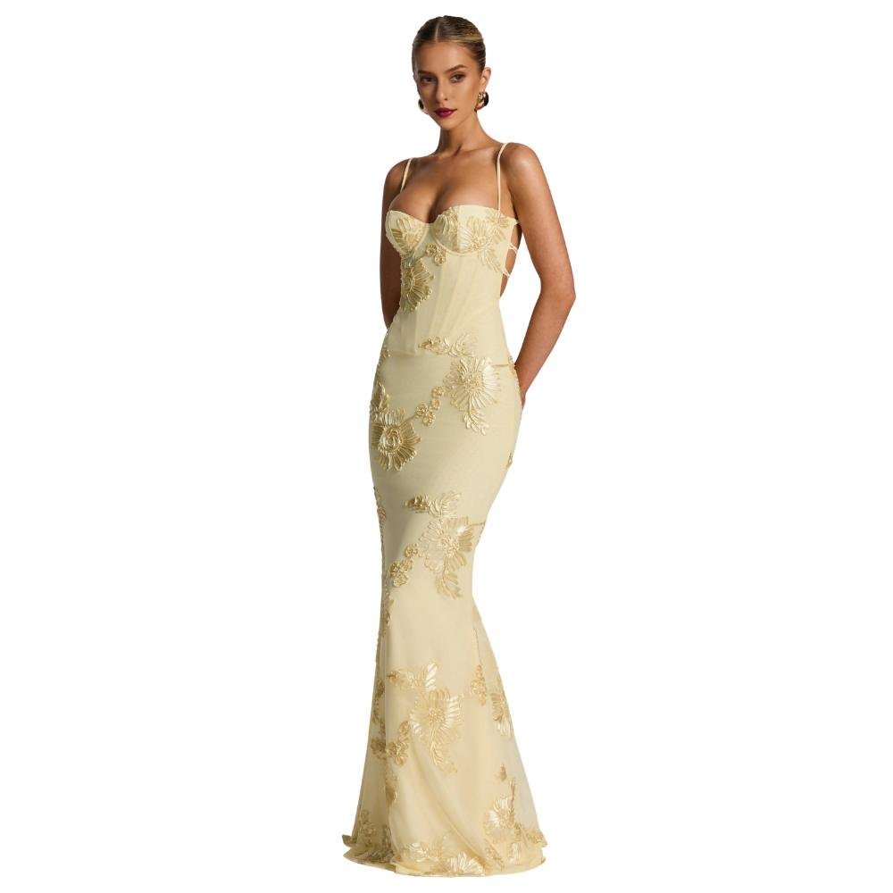 Woman wearing a yellow kouvr evening gown with floral lace details on a white background