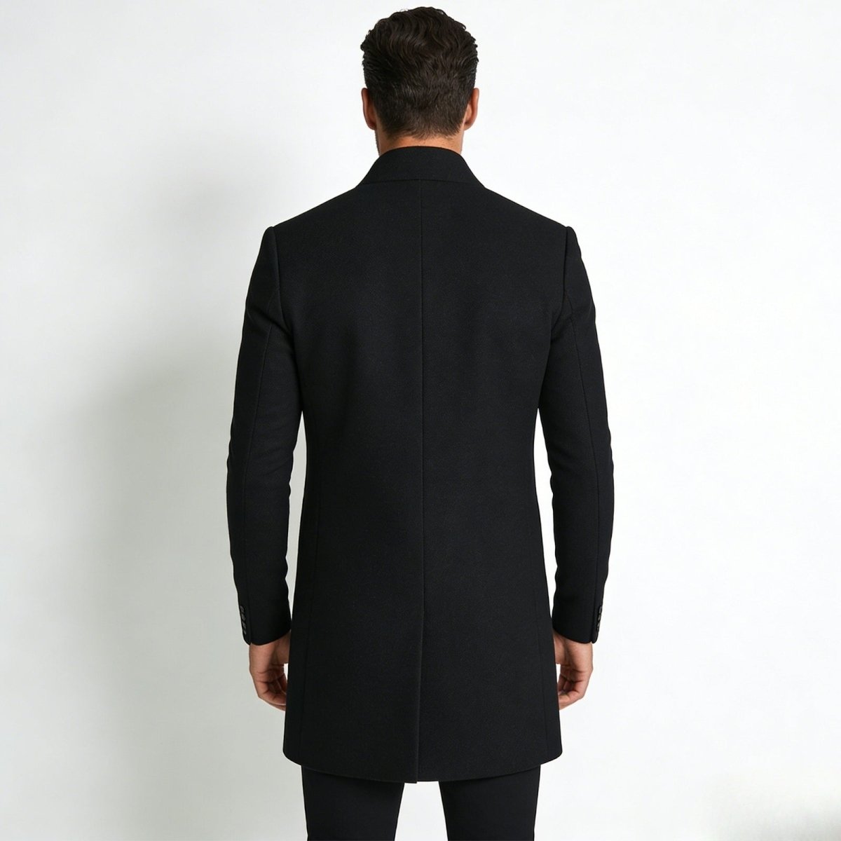 Back view of a male model wearing the Kouvr Fashion Archie black winter topcoat, highlighting the single back vent and structured shoulders.