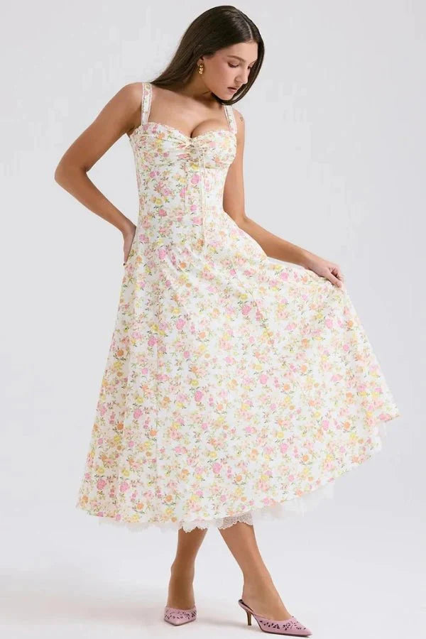 Model wearing Kouvr Fashion Aviva floral corset midi dress in white with pink and yellow flowers, showing the lace-up bustier and A-line skirt