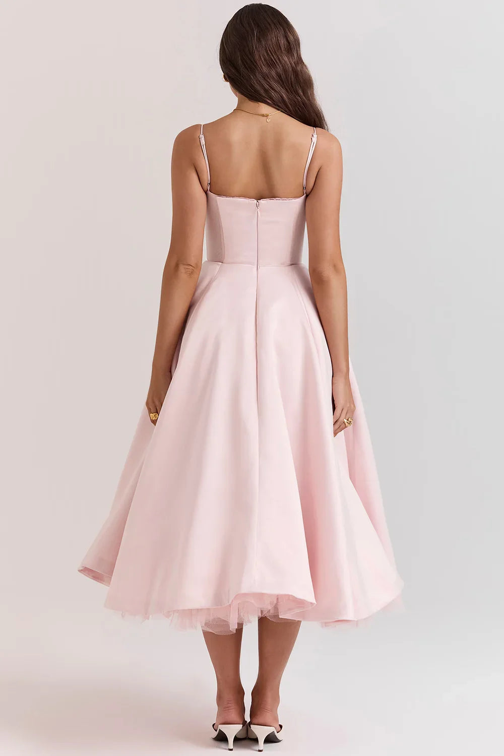 Model from the back wearing Kouvr Fashion's blush pink 1950s style fit and flare dress with a full tulle skirt