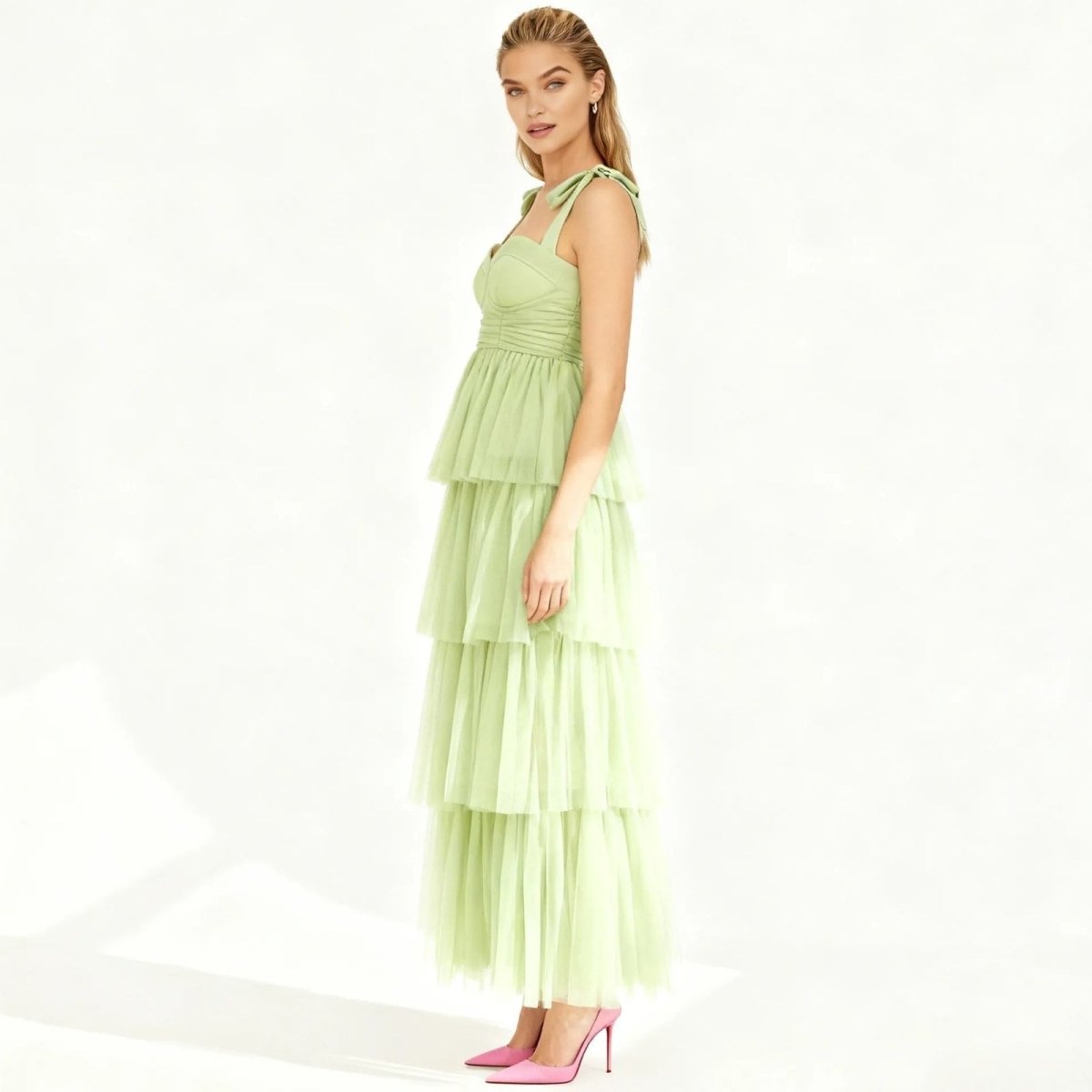 Woman wearing a light green Kouvr tiered dress on a white background