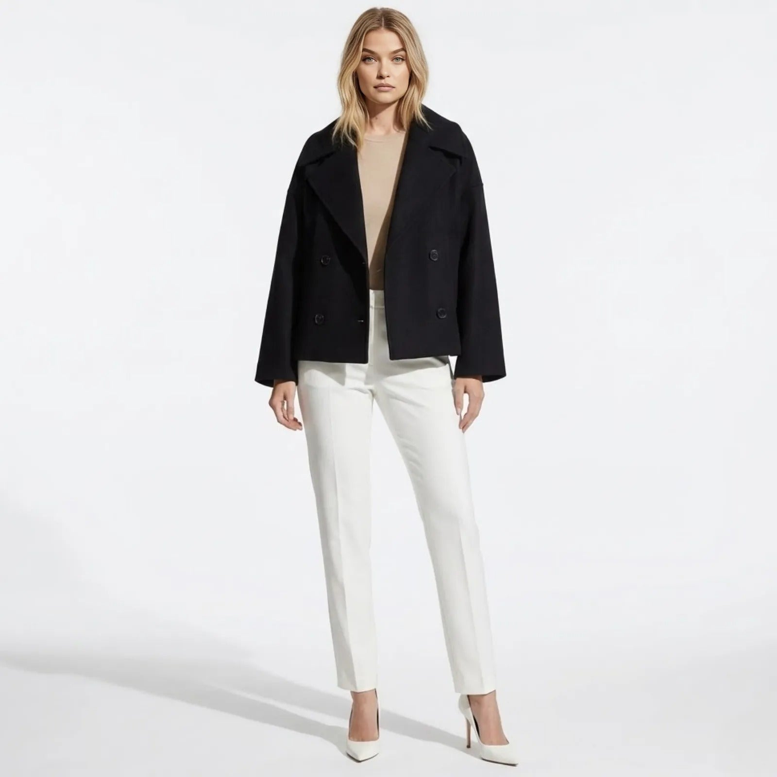 Model wearing the Kouvr Fashion black cropped double-breasted wool peacoat, styled with a beige top and white tailored trousers.