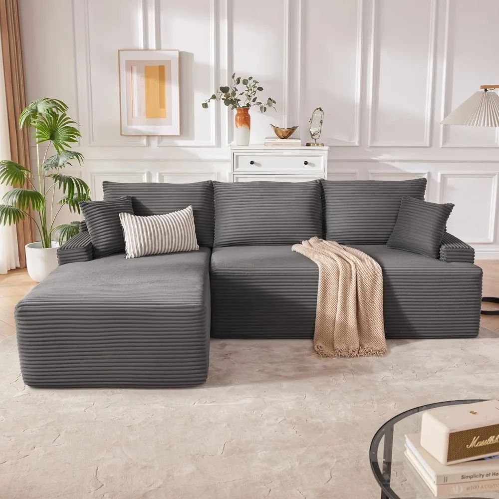 Kouvr modular deep seat sofa in black and dark grey corduroy shown in an L-shape with a beige throw blanket