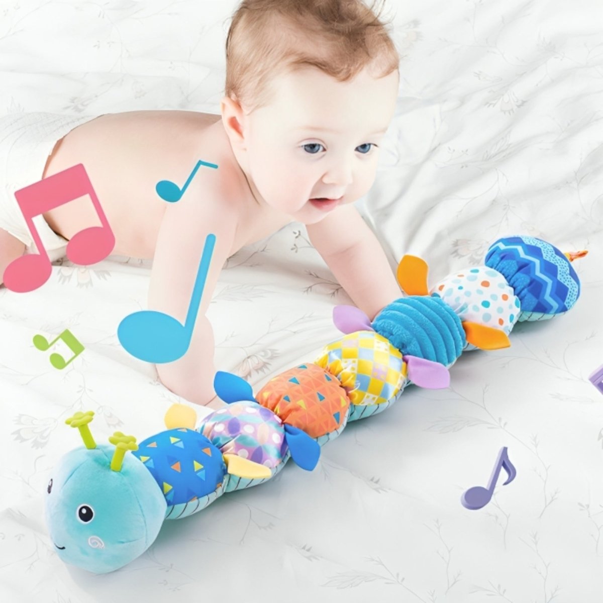 Baby playing with a colorful caterpillar toy on a white blanket