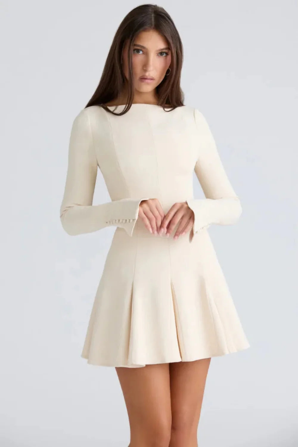 Model wearing the Kouvr Fashion Chessie long sleeve mini dress in white with button cuff details