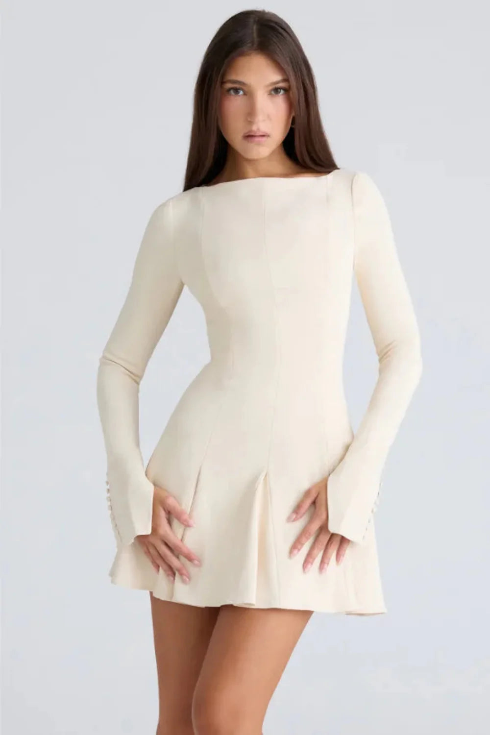 Model wearing the Kouvr Fashion Chessie long sleeve mini dress in white with button cuff details