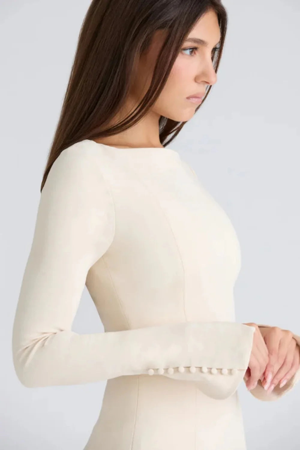 Model wearing the Kouvr Fashion Chessie long sleeve mini dress in white with button cuff details