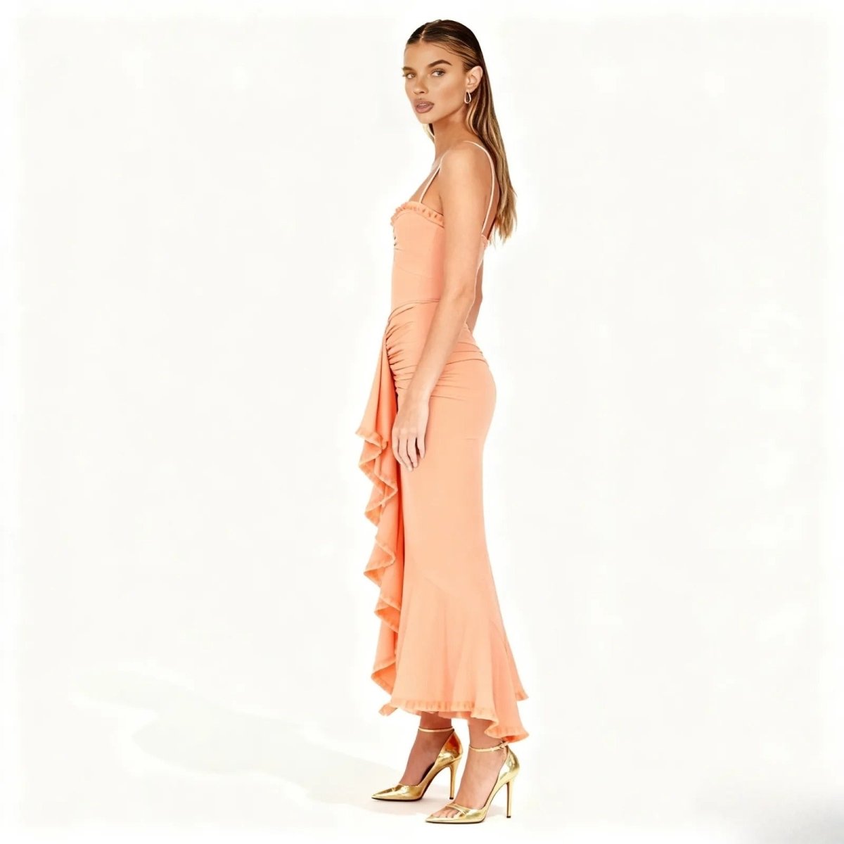 Woman wearing a peach dress with ruffled details on a white background