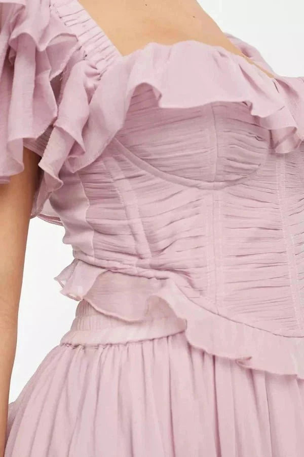 Model wearing Kouvr Fashion Freyna dusty lilac two-piece ruffle dress with corset top and tiered midi skirt