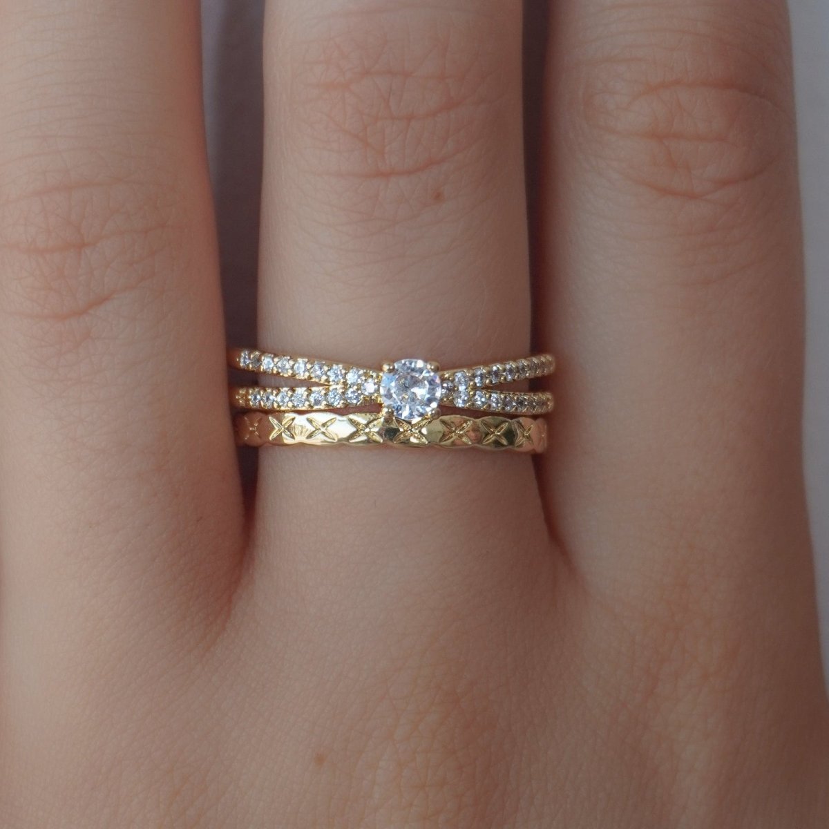 Gold kouvr ring with diamond on a finger against a neutral background