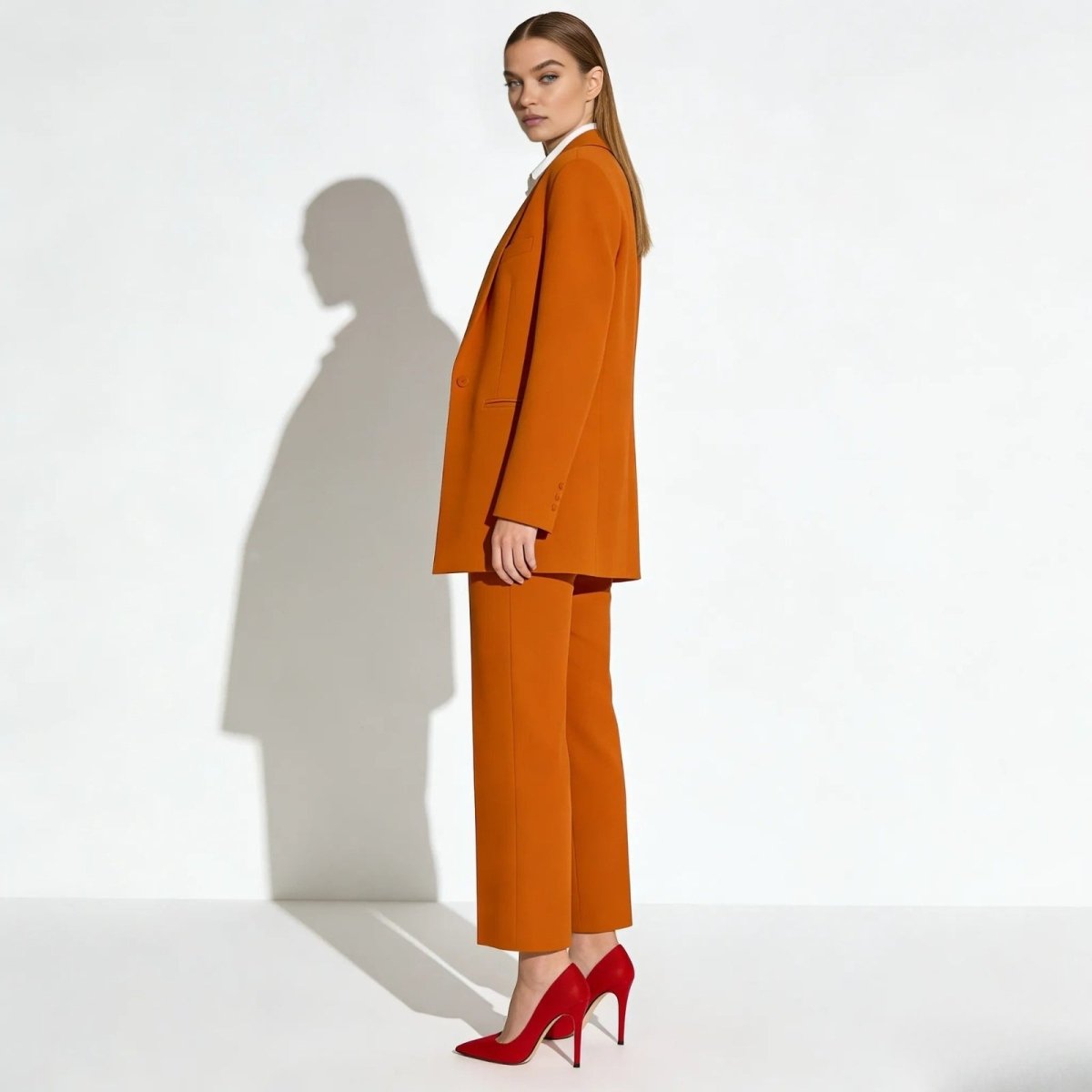 Side profile of a woman in a kate orange oversized blazer and matching trousers from Kouvr Fashion, showcasing the suit's silhouette and drape.