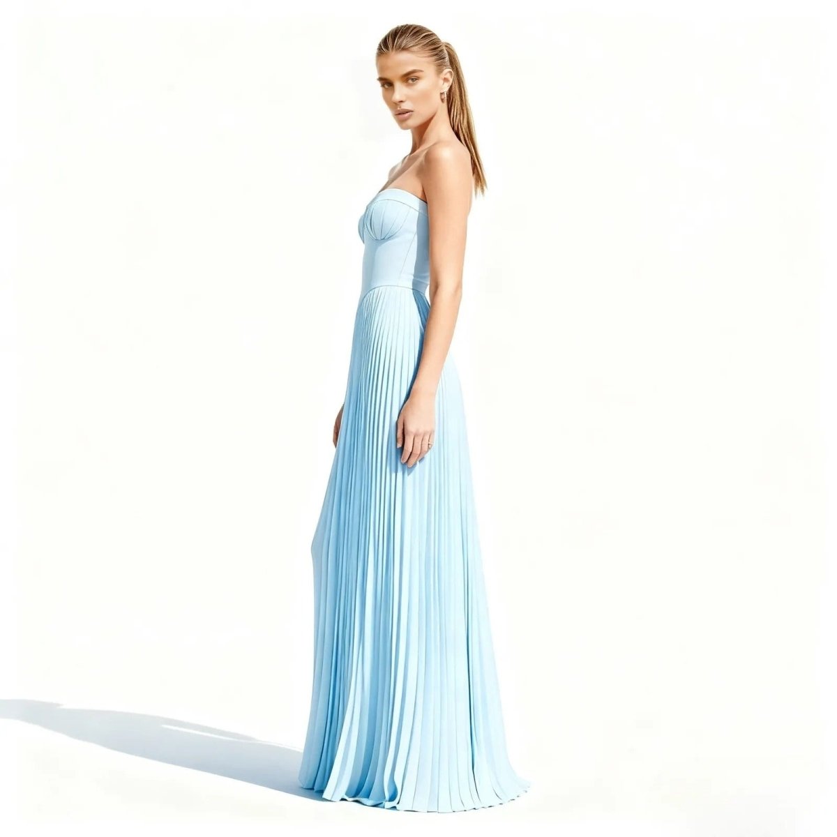 Woman wearing a light blue kouvr pleated gown on a white background