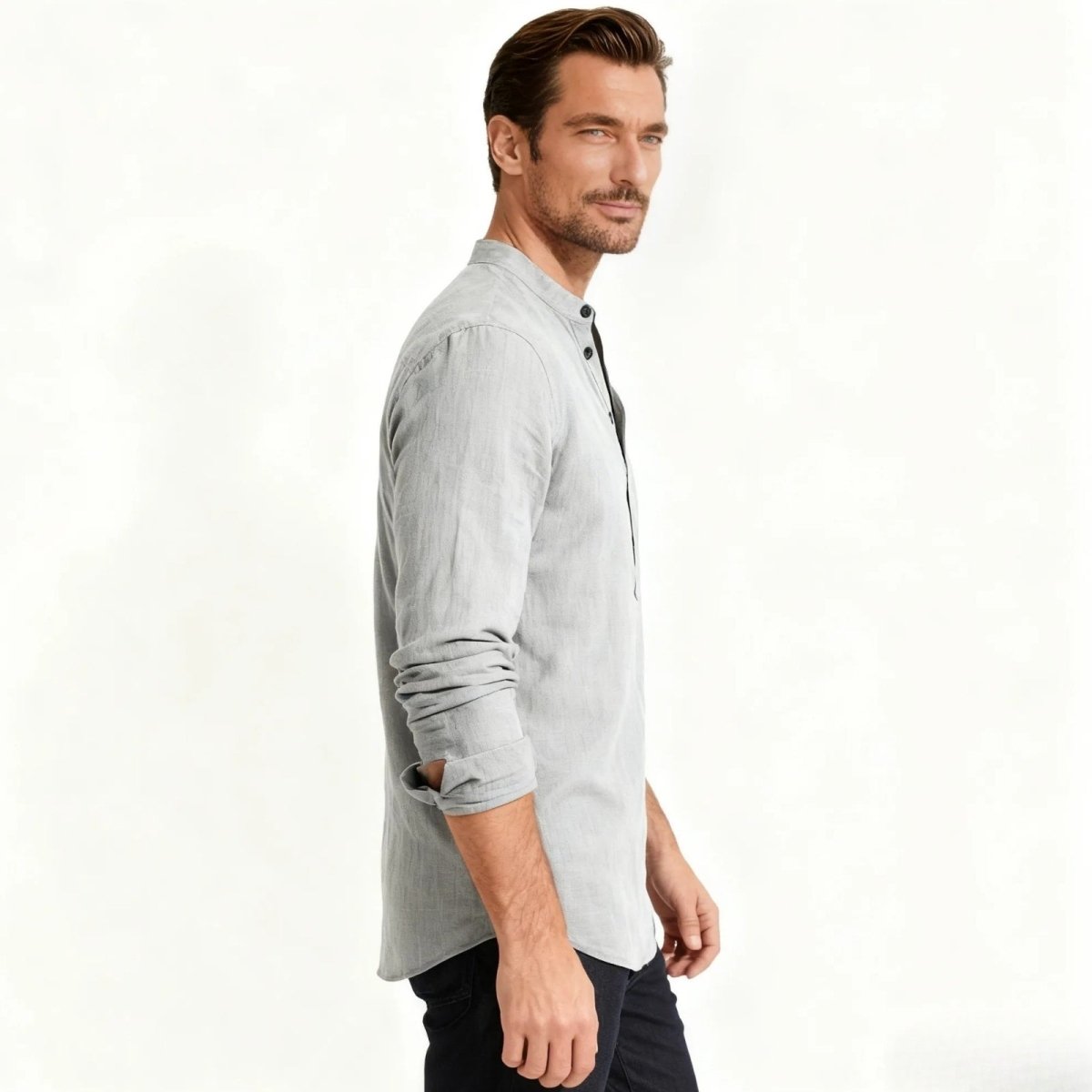 Side profile of a man in a sophisticated grey grandad collar long sleeve shirt from Kouvr Fashion, showing the slim fit and rolled cuffs.