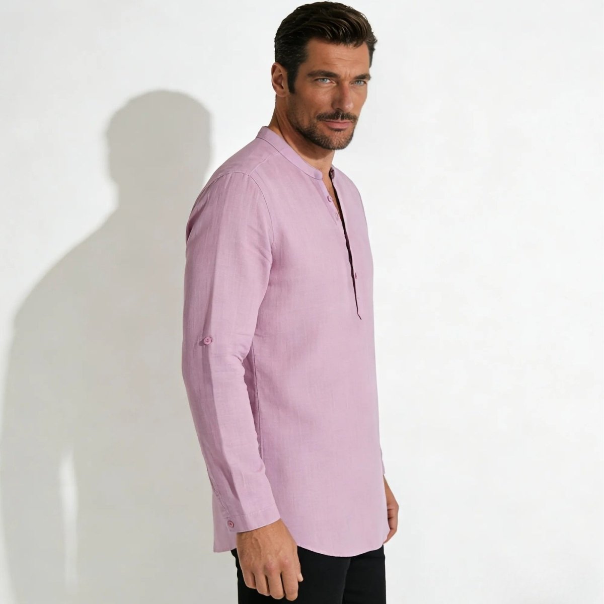 Side profile of a male model wearing the Kouvr Fashion roby pink long-sleeve shirt, showcasing its fit and the roll-tab detail on the sleeve.