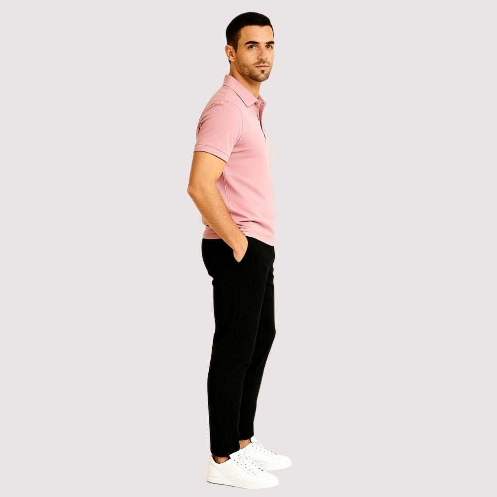 Man wearing the Kouvr slim fit Rose Quartz pink polo shirt with black trousers against a white background.