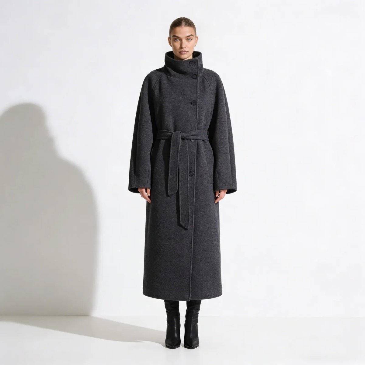 Model wearing the Kouvr Fashion Patrice long gray wool coat with a high funnel neck and tied belt, shown from the front against a white background.