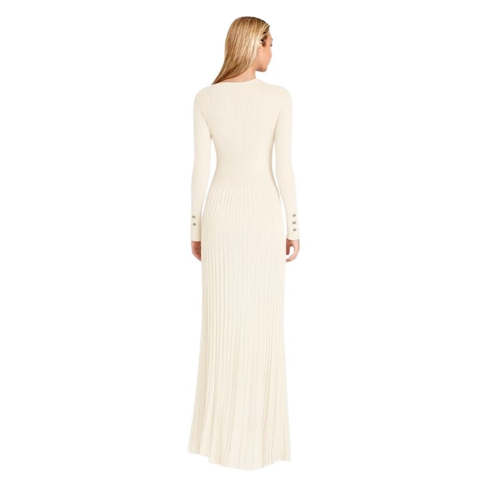 Model wearing the Kouvr Fashion long sleeve pleated knit maxi dress in cream, posing in a minimalist room