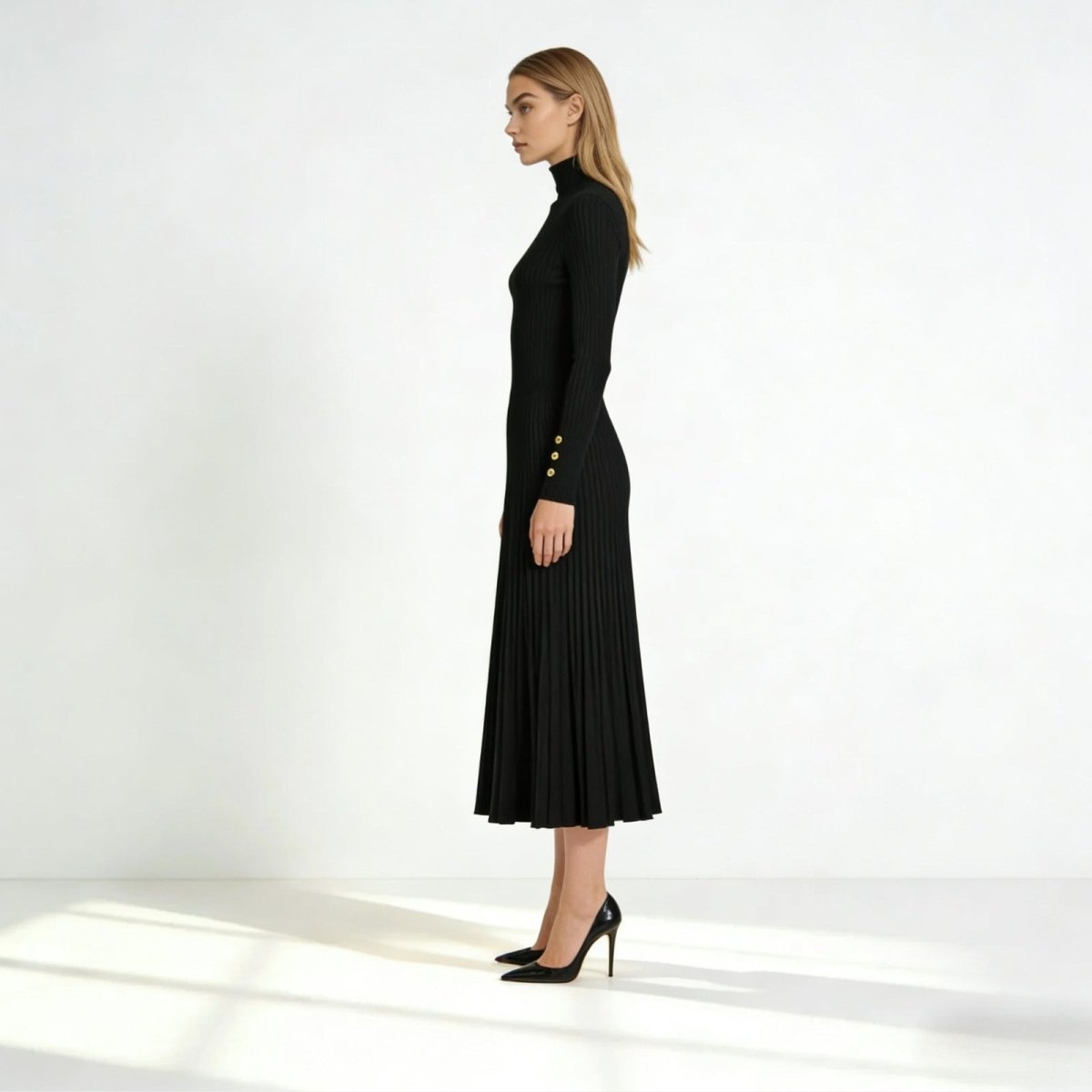 Side profile of the Kouvr Fashion long sleeve black pleated midi dress highlighting the gold button cuff detail and elegant silhouette.