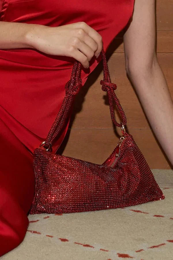 Model wearing a red satin dress holding the Kouvr Aria sparkly red hobo purse